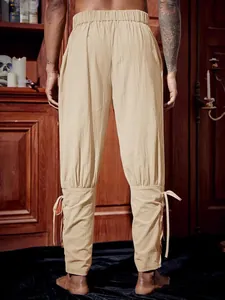 Back view of men's vintage beige pirate pants with drawstring ankle lace-up detail.