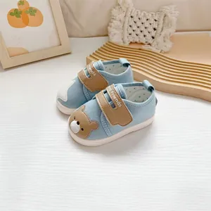 Detail van blauwe baby loopschoenen met schattig berenborduurwerk en klittenband.