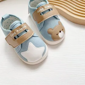 Detailopname van blauwe babyschoenen met cartoonbeer, ster en klittenbandsluiting.