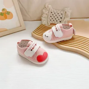 Detail van roze babyschoentjes met schattig konijntje en rood hartje borduursel