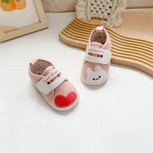 Gedetailleerde opname van roze babyschoentjes met schattige hartjes- en konijnenborduurpatches
