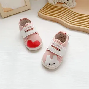 Detailweergave roze canvas babyschoenen met schattige konijn en hart.