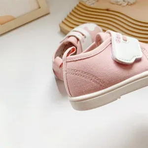 Detailopname van roze baby loopschoentjes met zachte zolen en klittenbandsluiting.