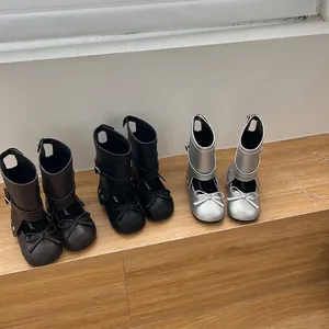 Λεπτομέρεια από δερμάτινες μπότες για κορίτσια με φιόγκο σε μαύρο, καφέ και ασημί.