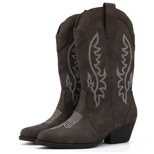 Detailed view of the intricate white embroidery on dark brown suede cowboy boots.
