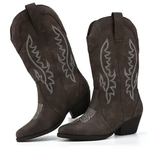 Close-up detail of dark brown women's cowboy boots with white intricate embroidery.
