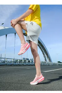 Chaussures de course roses montrées en action sur une route de pont en plein air.