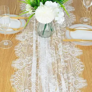 Detail view of white floral lace table runner on a wooden dining table.