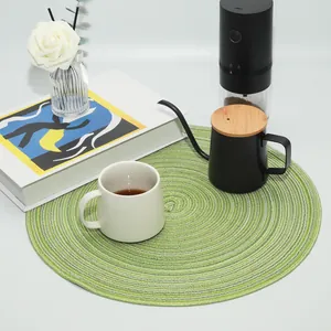 Close-up detail of a green spiral woven round placemat with cozy coffee props.
