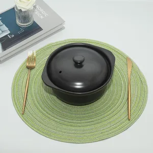 Green and yellow spiral woven round placemat styled with black pot and gold cutlery