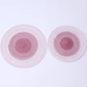 Close-up view of two circular gradient woven cotton placemats in pink and white tones.
