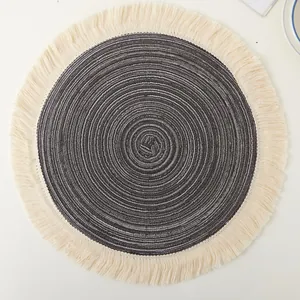 Top-down view of a circular woven cotton placemat featuring decorative cream fringes