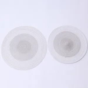 Macro detail of round woven cotton placemats featuring a minimalist grey gradient design