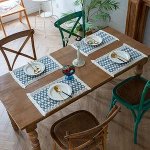Set of four blue geometric woven cotton linen placemats with fringes on a wood table