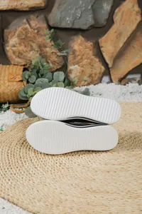 Vista detallada de la suela blanca antideslizante para los mocasines negros flyknit