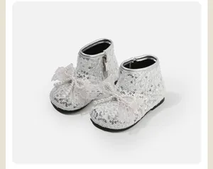 Gedetailleerd macrozicht op sprankelende zilveren pailletten babyboots met parelstrik