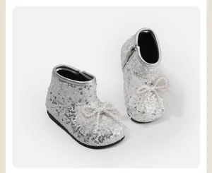 Gedetailleerde weergave van zilveren pailletten babyschoentjes met kantstrik en parels