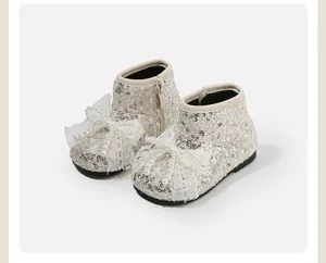 Detail van glinsterende pailletten babyschoentjes met kanten strik en parel accenten