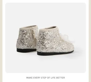 Detailweergave van zilveren pailletten babyschoenen met een mesh-strik en ritssluiting