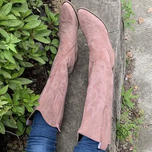 Detailed view of vintage Western cowboy boots with white embroidery on pink suede