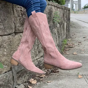 Detail view of pink suede western cowboy boots featuring white floral embroidery and block heel
