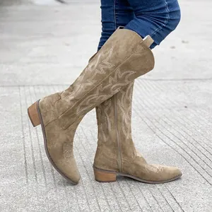 Detailed view of brown suede Western cowboy boots with white embroidery and chunky heel