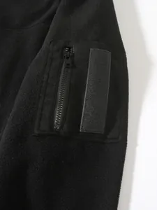 Close-up detail of black fleece jacket sleeve showing zippered pocket and velcro strip attachment