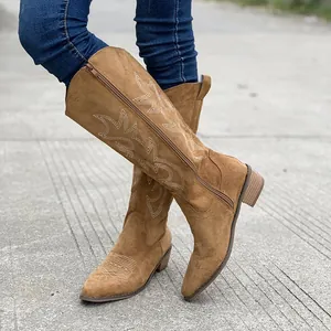 Detailed view of brown suede cowboy boots with white vintage embroidery and chunky heel