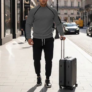 Professional man in grey fleece pullover and black joggers set with a silver suitcase.