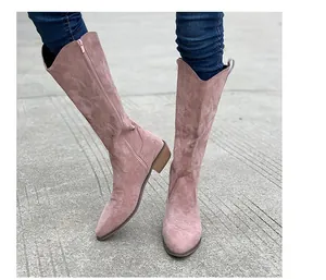 Close-up of pink suede cowboy boots featuring vintage embroidery and V-shaped top design