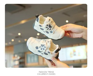 Detail von cremefarbenen Baby-Lauflernschuhen mit süßem Pfoten-Design und Klettverschluss