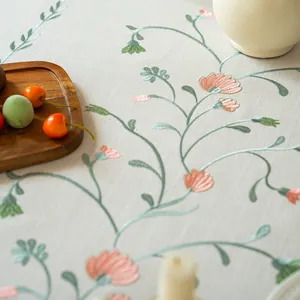 Macro view of detailed pink floral and green vine embroidery on tablecloth