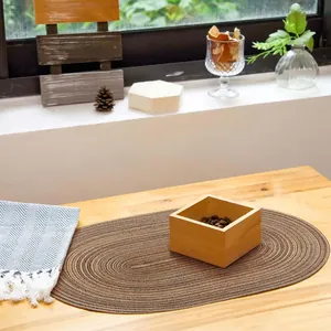 Mantel individual ovalado marrón moderno y minimalista en una mesa de madera de estilo vida.