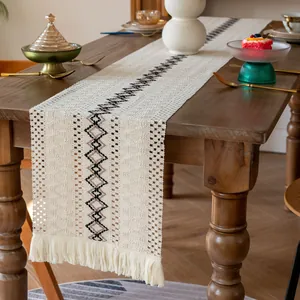Détail du chemin de table bohème en coton avec motif géométrique noir et glands décoratifs.