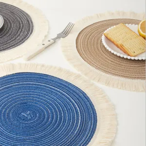 Detailed close-up of woven cotton yarn placemats featuring fringe edges in blue and tan.
