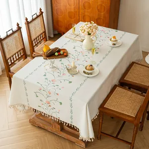 Elegant floral embroidered tablecloth with tassel fringe for rustic dining decor.