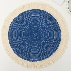Macro view of a blue woven round placemat with delicate cream cotton fringe detail