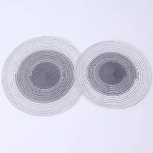 Detail view of two circular Nordic gradient woven placemats in gray and white colors