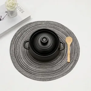 Macro detail of a grey round woven heat-resistant placemat under a black ceramic pot