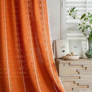 Detailed view of orange textured semi-blackout curtain with white tassel edges