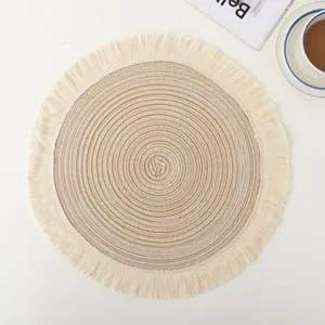 Macro view of round cotton woven placemat with elegant beige tassel fringe details.