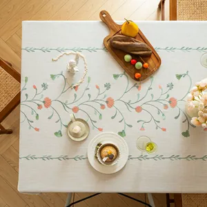 Top-down view of an elegant beige tablecloth decorated with embroidered floral patterns