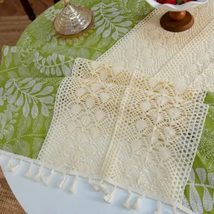 Vue détaillée d'un chemin de table vintage en crochet crème avec dentelle et glands