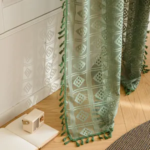 Dettaglio della tenda all'uncinetto verde salvia con motivi traforati e nappe eleganti