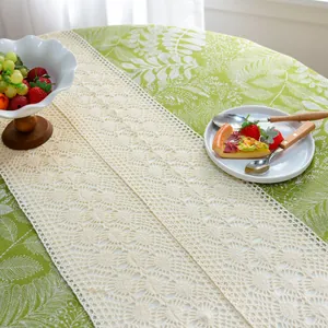 Gros plan d'un chemin de table en dentelle au crochet beige sur nappe fleurie