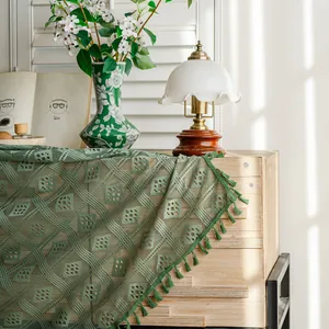 Dettaglio di una tenda all'uncinetto verde traforata con nappe su legno