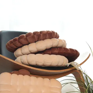 Close-up view of soft plush biscuit-shaped round cushions in coffee and beige colors