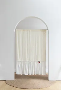 Detail of white cotton doorway curtain featuring orange dots and cherry ornament