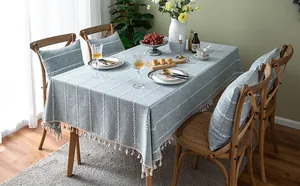 Detailed view of light blue tablecloth with white stitched stripes and tassel fringe