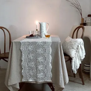 Vista detallada del camino de mesa de encaje blanco bordado con motivos florali decorativos